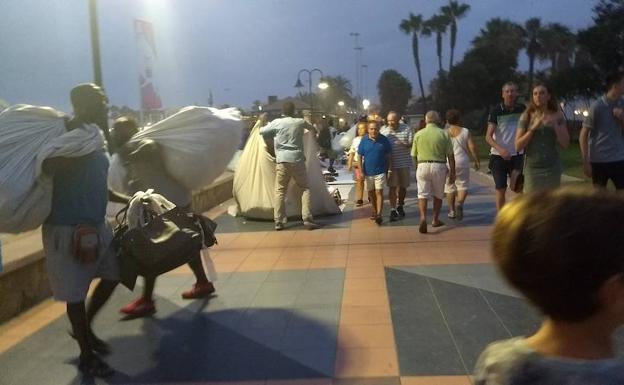 Vendedores ambulantes recogen sus mantas en el paseo marítimo entre Torremolinos y Benalmádena