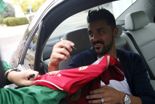 Villa, firma una camiseta ayer al llegar a Las Rozas. :: mariscal. efe