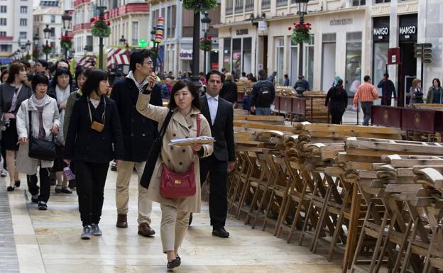 Un grupo de turistas asiáticos se sorprenden en su paseo por la calle Larios del montaje que se organiza para Semana Santa (archivo). /Ñito Salas