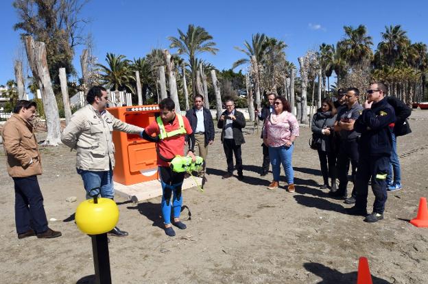 Un socorrista explica el funcioamiento del dispositivo con el edil de playas. /Josele-Lanza -