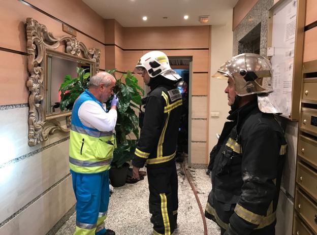 Un miembro del 112 y dos bomberos, ayer en el descansillo de la vivienda de Getafe. :: 112/