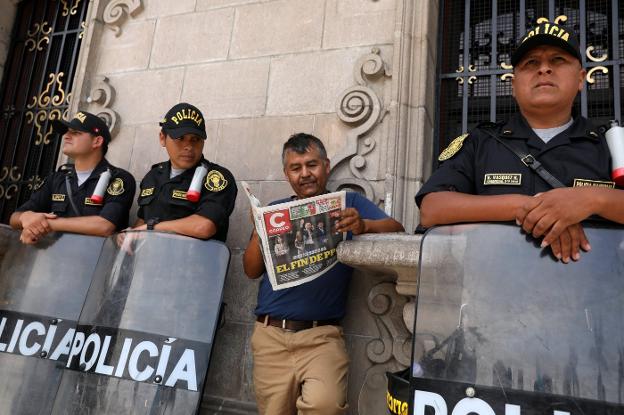 Un hombre lee el periódico en medio de un dispositivo de seguridad, ayer cerca del Palacio de Gobierno en Lima. :: Mariana Bazo / reuters/