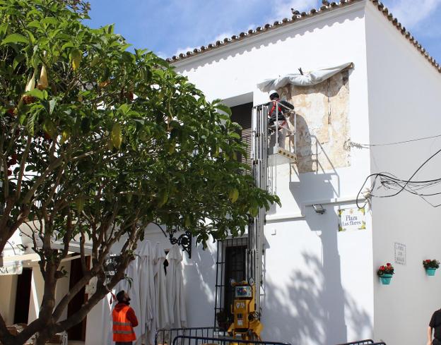 Trabajos de recuperación de la pintura en la fachada de una vivienda de la plaza de Las Flores. /Ch. Márquez