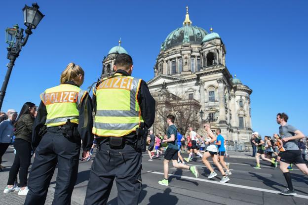 Dos policías vigilan, ayer, a los participantes y espectadores del maratón de Berlín. :: Christophe Gateau / afp/