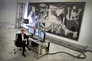 El director del Reina Sofía posa frente al 'Guernica' y al robot que estos días escanea la obra de Pablo Picasso para precisar su estado de conservación. :: ALBERTO FERRERAS/