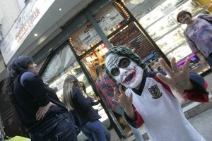 Un niño muestra una máscara a las puertas de una concurrida tienda de disfraces. :: Yhasmina García/