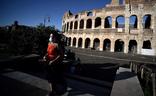 Una mujer protegida con una mascarilla pasea por el centro de Roma, con el Coliseo al fondo./AFP